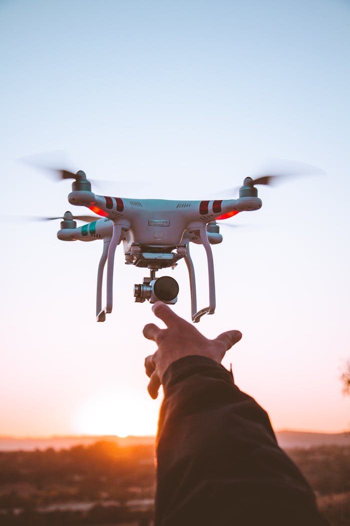 A person launching a drone at sunrise against a clear sky, capturing a moment of technology and adventure.